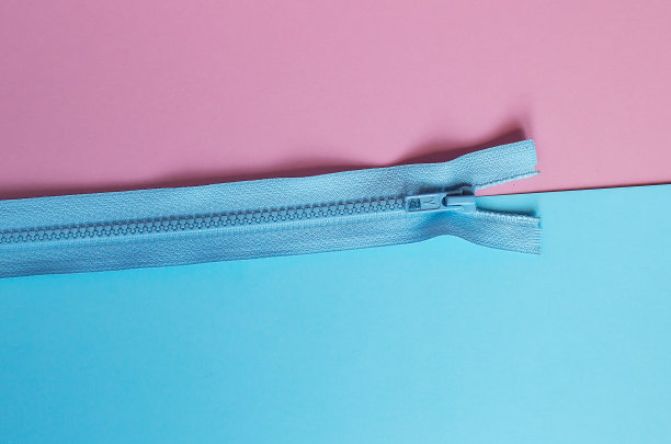 工作地点裁缝。缝纫是我的爱好。粉色和蓝色背景的衣服拉链。图片下载