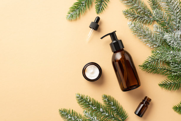 天然护肤品概念。俯视图照片化妆品瓶没有标签滴管瓶霜罐和松枝在白霜孤立的米色背景与空白图片下载