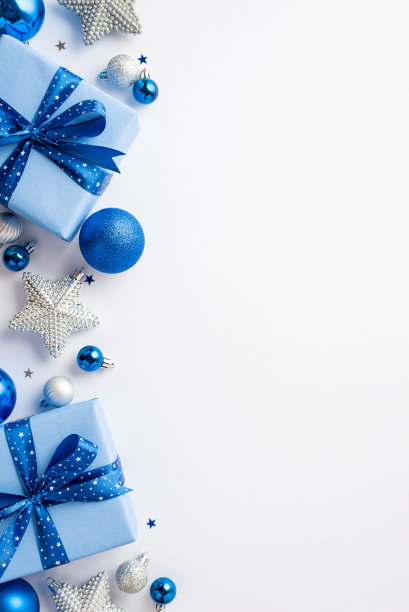 新年的概念。顶视图垂直照片的礼物盒丝带蝴蝶结蓝色白色银饰和星星饰品孤立的白色背景与空白图片下载