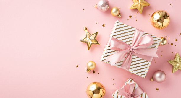 新年美学观念。顶视图照片的时尚礼盒与粉色丝带蝴蝶结金粉色小饰物明星饰品和发光的五彩纸屑孤立的浅粉色背景与copyspace图片下载