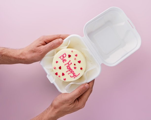 男子拿着便当蛋糕，上面写着“快乐在外卖盒里”图片下载