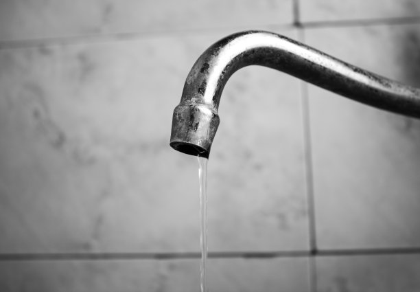 浴室里一个旧水龙头流出的细流。一个旧水龙头。图片下载