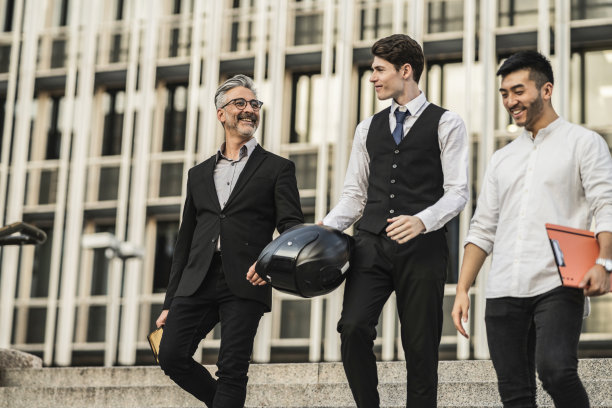 三个多种族的商人带着摩托车头盔离开工作图片下载