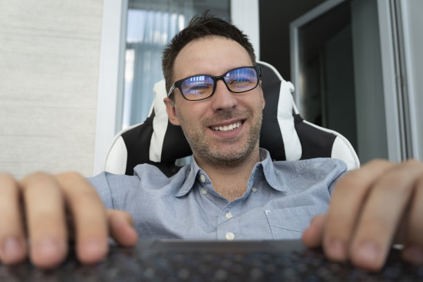 一个快乐的员工在办公室工作。职业文案，自由撰稿，键盘打字。快乐的商人使用笔记本电脑，计划创业，坐在现代化的办公室。图片下载