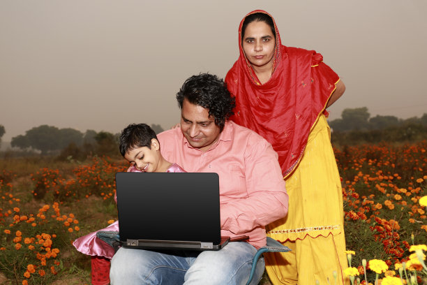 一家人一起在花地里使用笔记本电脑图片下载