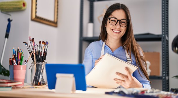 年轻的女艺术家在艺术工作室用触控板在笔记本上画画图片下载