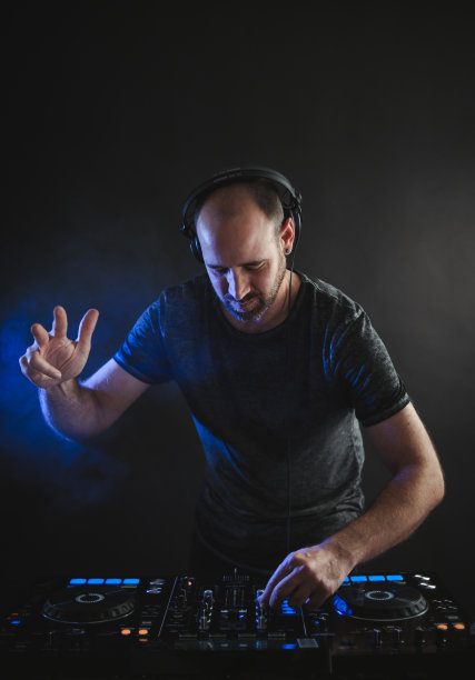 一名男性DJ在录音棚的蓝色灯光下工作的垂直图片图片下载