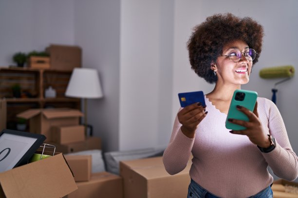 非裔美国妇女在新家使用智能手机和信用卡图片下载
