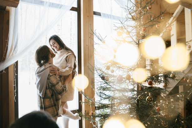 拥抱时尚的爱夫妇女孩，男孩躺在舒适的木制乡村房子的地板上皮肤，小屋在冬天的森林。庆祝除夕。礼物,家庭假期。浪漫的周末。装饰圣诞树图片下载