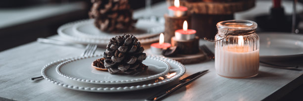 圣诞或新年家庭晚餐的乡村餐桌装饰。配红蜡烛，干橙，圆锥形，肉桂，八角。零废物环保家居。舒适的氛围，深色的背景。横幅图片下载