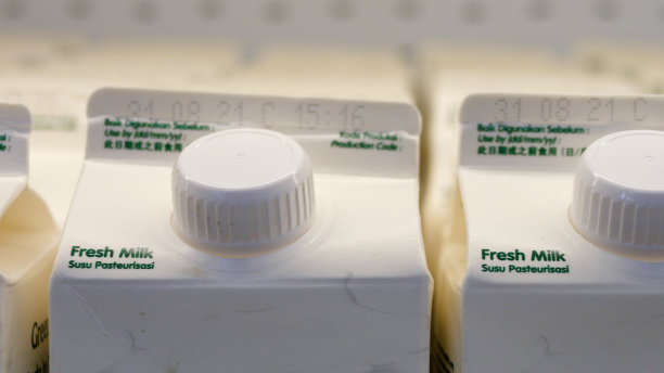 超市冰箱里一排排鲜奶白色盒子的特写。全球人口购买牛奶和乳制品。货架上有一排白色牛奶盒待售。图片下载