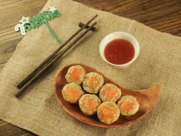 蒸饺、点心或饺子装在木制托盘上，筷子上装饰着圣诞装饰。图片下载