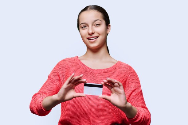 十几岁的学生女孩展示银行信用卡，在白色的工作室背景图片下载