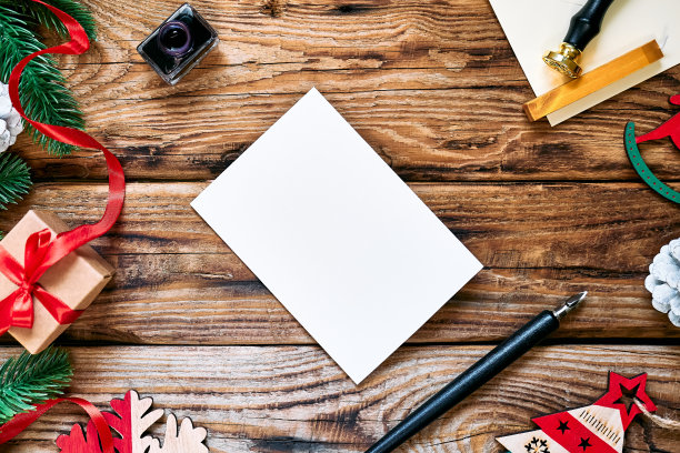 邮件信封和白色的纸制作的文字与自来水笔和墨水瓶在木制背景与圣诞装饰。给圣诞老人的信，愿望清单，要做的事清单，新年的梦。图片下载