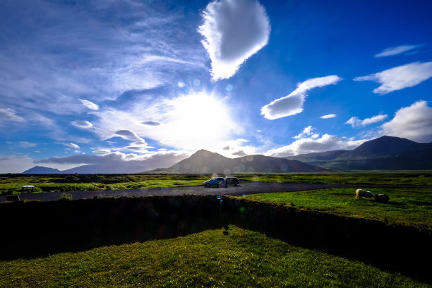 美丽的照片，汽车停在草地中间的道路上，远处有山图片下载