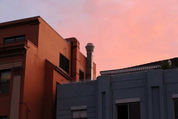 粉红色的天空下棕色和灰色的房子图片下载