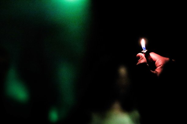 一个人拿着一个点燃的打火机和一个黑暗的背景的选择性聚焦镜头图片下载