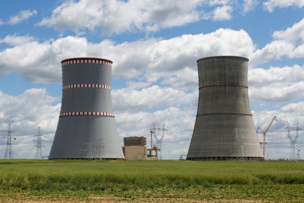 草地上有工厂的冷却塔，背景是多云的天空图片下载