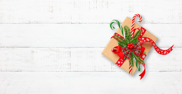 圣诞礼品盒装饰红色蝴蝶结，糖果拐杖，云杉树枝和冬青浆果在白色的木制背景。图片下载