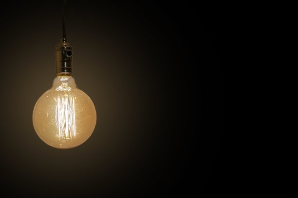 一个老式黄色灯泡在黑色背景上反射光线的特写镜头图片下载