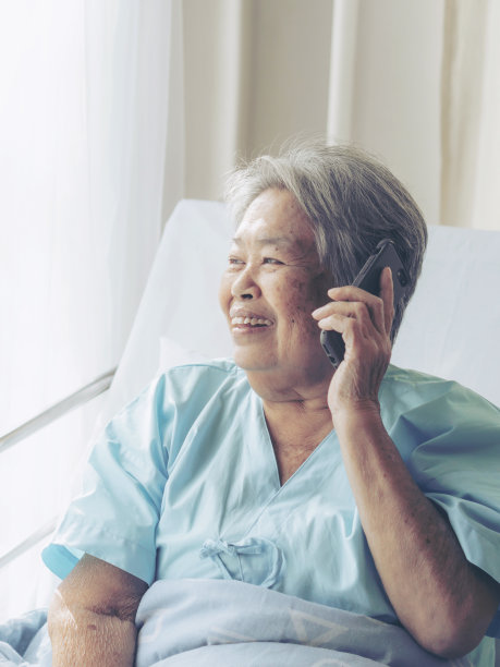 老年患者在医院病床上用智能手机给后代亲属打电话感受幸福——医疗保健理念图片下载