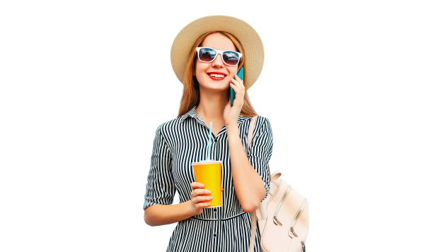 画像的快乐微笑的妇女打电话的智能手机杯果汁戴草帽，背包孤立在白色背景图片下载