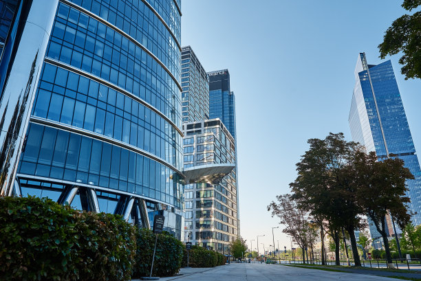 现代城市建筑，摩天大楼玻璃立面绿树图片下载