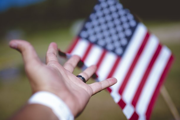 近景一个人的手对美国国旗与模糊的背景图片下载