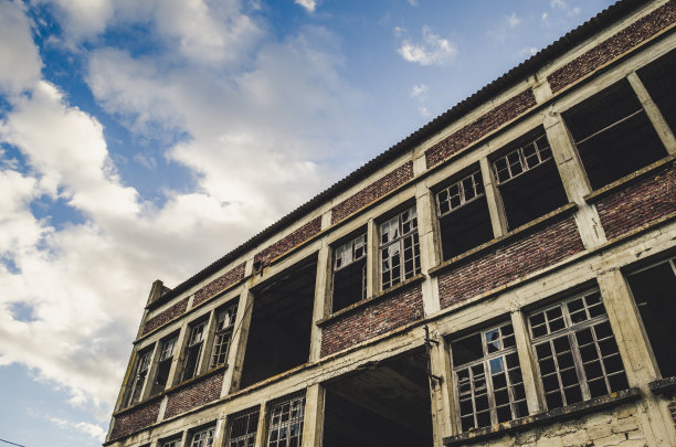 被树木和绿色植物包围的废弃砖房的垂直镜头图片下载