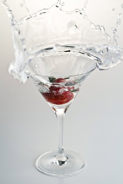 垂直拍摄的草莓落入一杯水和水的飞溅图片下载