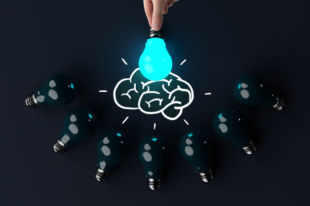一只手拿着一个亮着的灯泡，背景是其他熄灭的灯泡和大脑的草图。图片下载