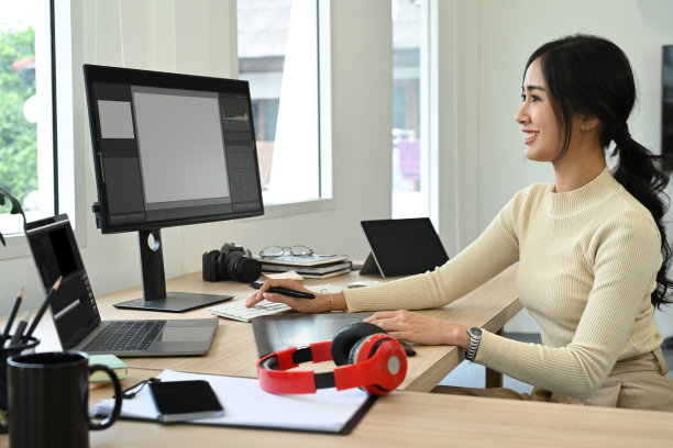 迷人的女照片编辑坐在创造性的工作场所，在人事电脑上修饰照片。图片下载