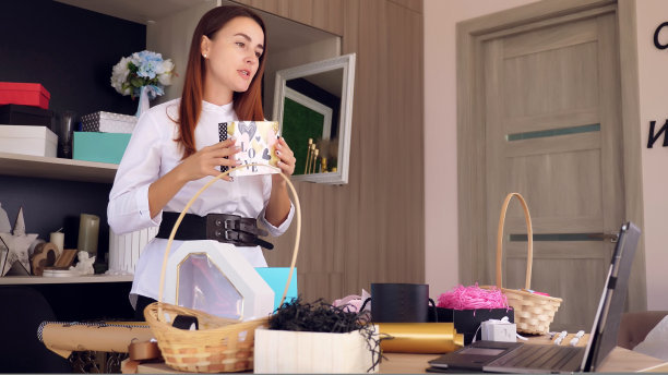 礼品和装饰设计师进行在线培训，视频会议。，记录视频博客，网络研讨会，站在笔记本电脑前。在线工作。图片下载