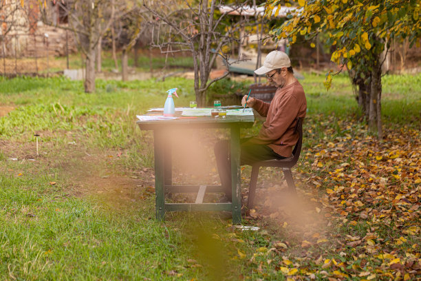 成熟的艺术家坐在花园里画画图片下载