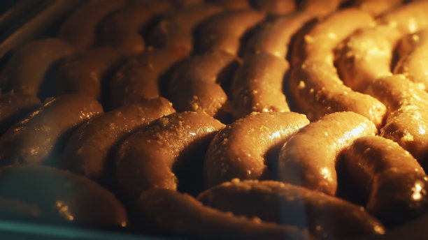 特写，自制香肠烹饪过程在一个大型工业烤箱，在一个工业餐厅的厨房。美味的自制烤香肠在烤箱图片下载