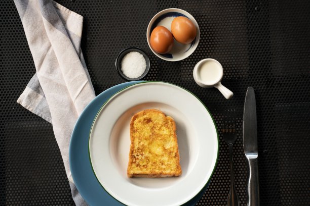 头顶上白色盘子上的法式吐司，旁边是鸡蛋和奶油图片下载