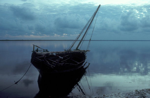 美丽的木船在水面上的照片，背景是多云的天空图片下载