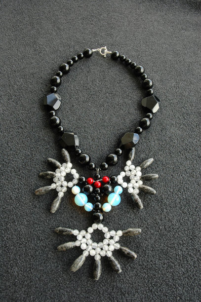 垂直拍摄的项链由黑色，红色，蓝色和白色的珠子在灰色的表面图片下载