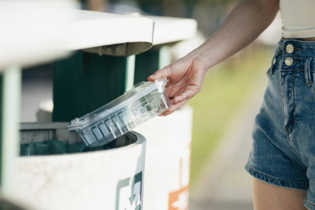 妇女把垃圾放入不同类型的塑料容器图片下载
