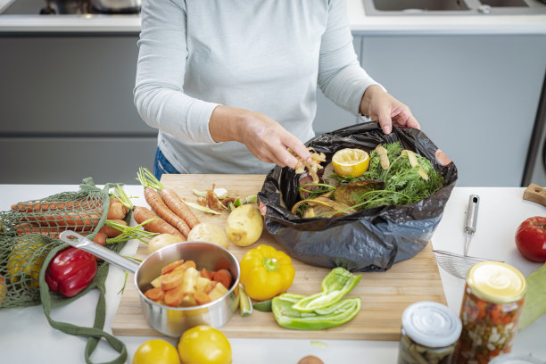 妇女回收蔬菜皮在一个垃圾袋图片下载