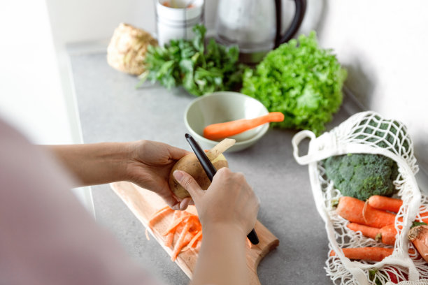 女人的手削土豆皮，把土豆皮放进碗里回收。图片下载