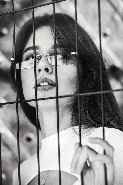 近距离肖像的女人在一个白色blause附近的金属网格图片下载