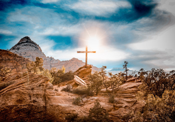 美丽的沙漠照片，有树木和岩石上的十字架，阳光照耀在多云的天空图片下载