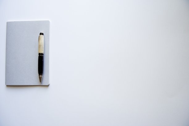 头顶上的一个记事本，在白色的表面上有一支笔图片下载