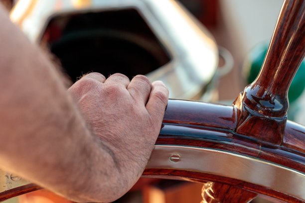 特写镜头一个男人的手握着一艘船的轮子-接管指挥你的生活概念图片下载