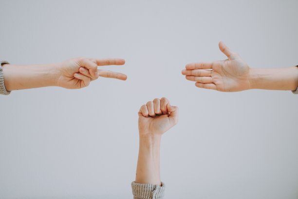 三个人在灰色背景下玩石头剪刀布游戏的广角镜头图片下载