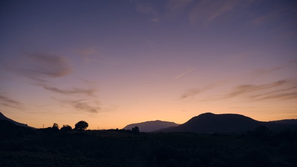 落日时分，蓝色和黄色天空下山丘和山脉的剪影图片下载