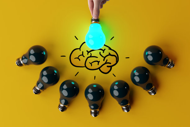 一只手拿着一个亮着的灯泡，背景是其他熄灭的灯泡和大脑的草图。图片下载