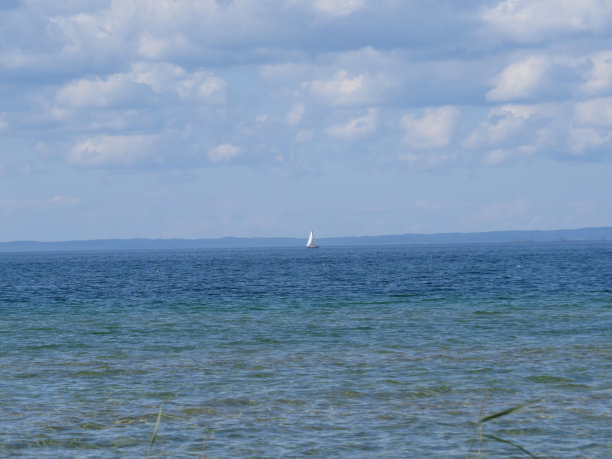 湛蓝的大海和远处一艘白色帆船的美丽照片图片下载
