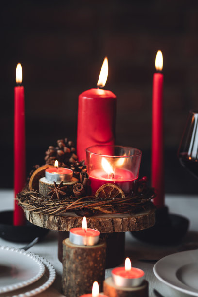 圣诞或新年家庭晚餐的乡村餐桌装饰。配红蜡烛，干橙，圆锥形，肉桂，八角。零废物环保家居。舒适的氛围，深色的背景。近距离图片下载